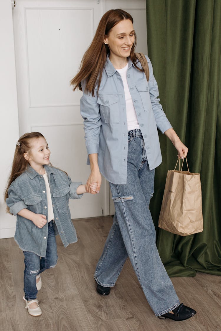 Mother And Daughter In Denim Clothes Walking With Holding Hands