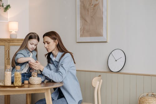 A Child in Denim Jeans and a Woman in Blue Long Sleeves Shirt Sitting