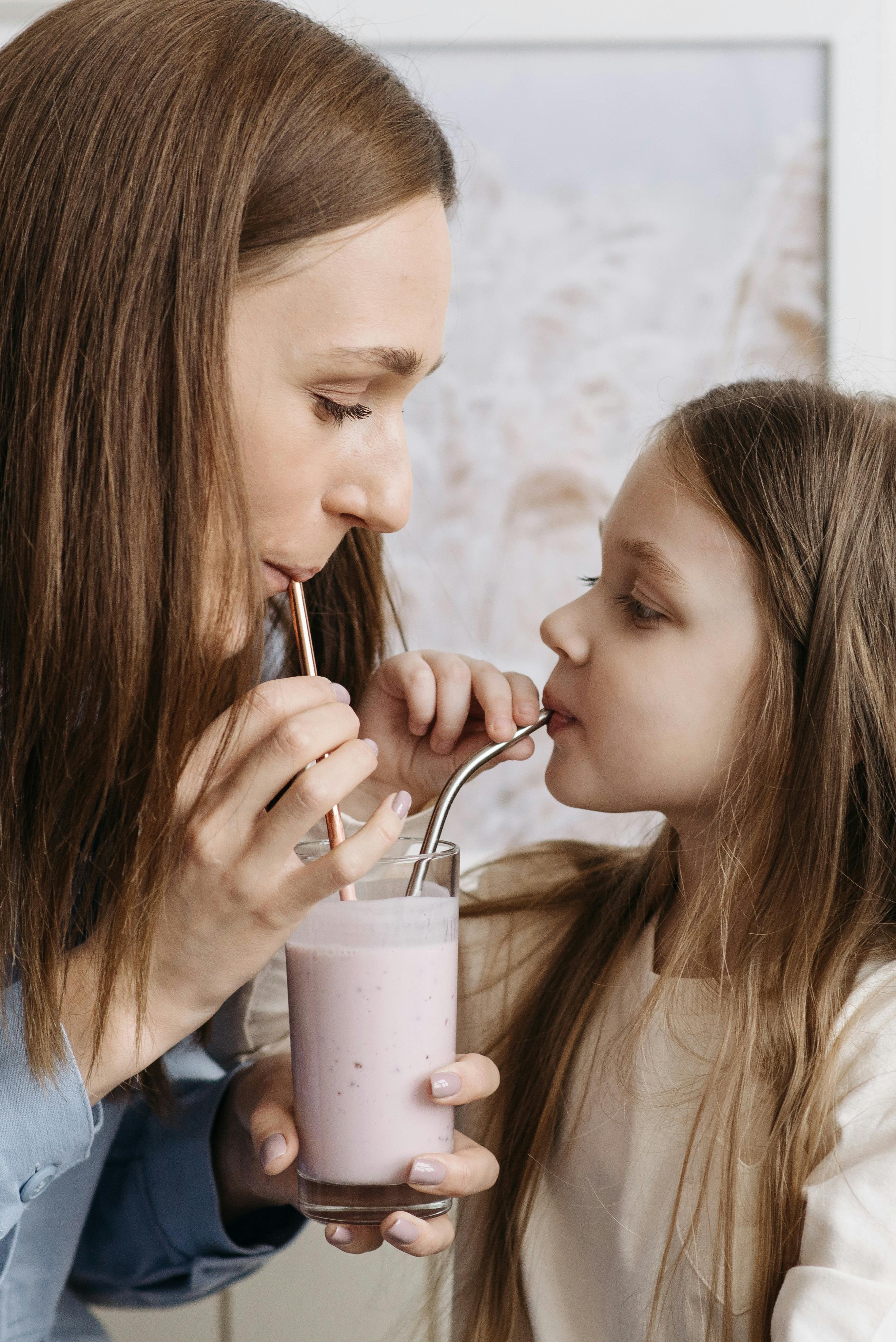 woman and child sipping on stainless steel straws in a glass of milkshake