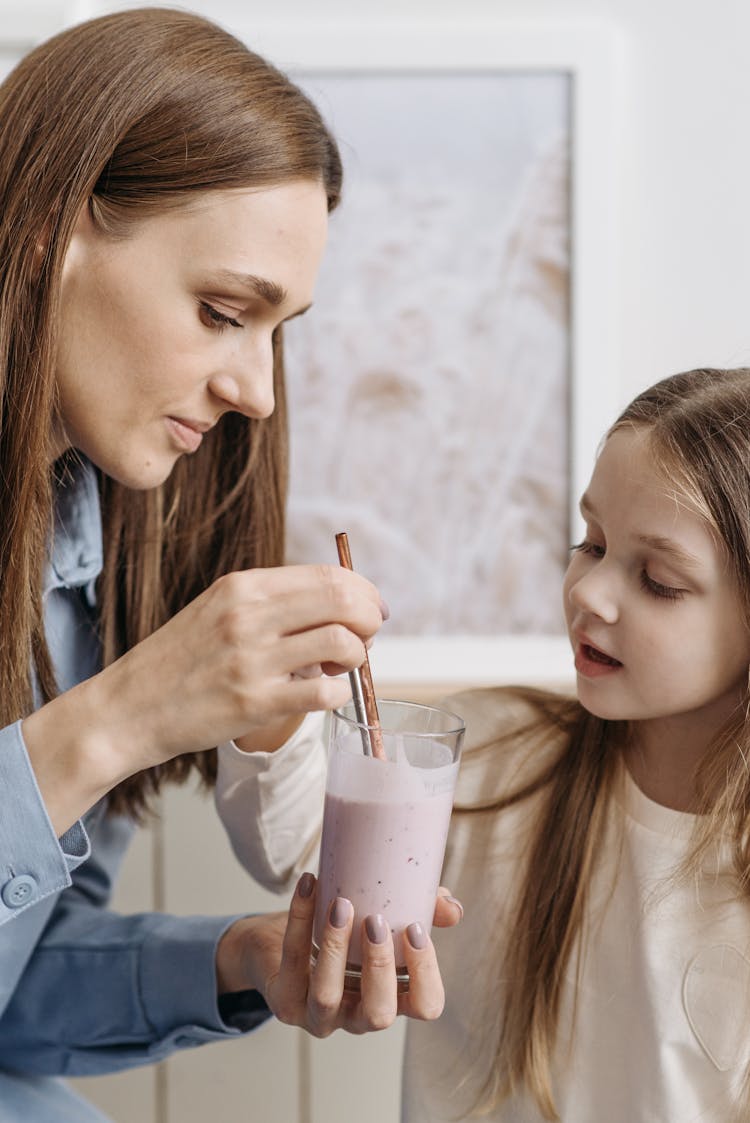 A Woman And A Child Holding A Glass Of Drink