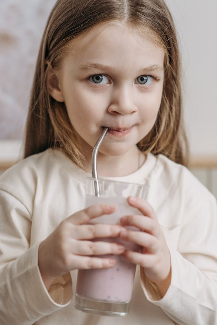 A Child Sipping From A Stainless Steel Straw Holding A Glass Of Milkshake 