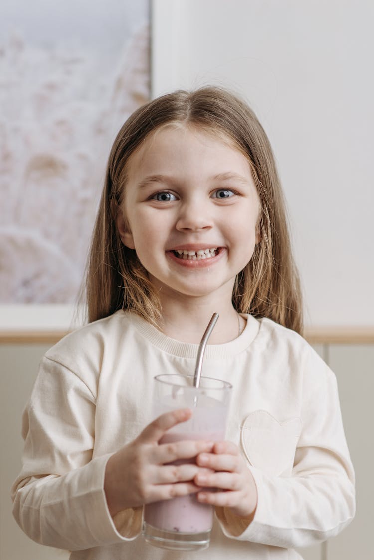 Smiling Child Holding A Glass With Straw Looking At The Camera