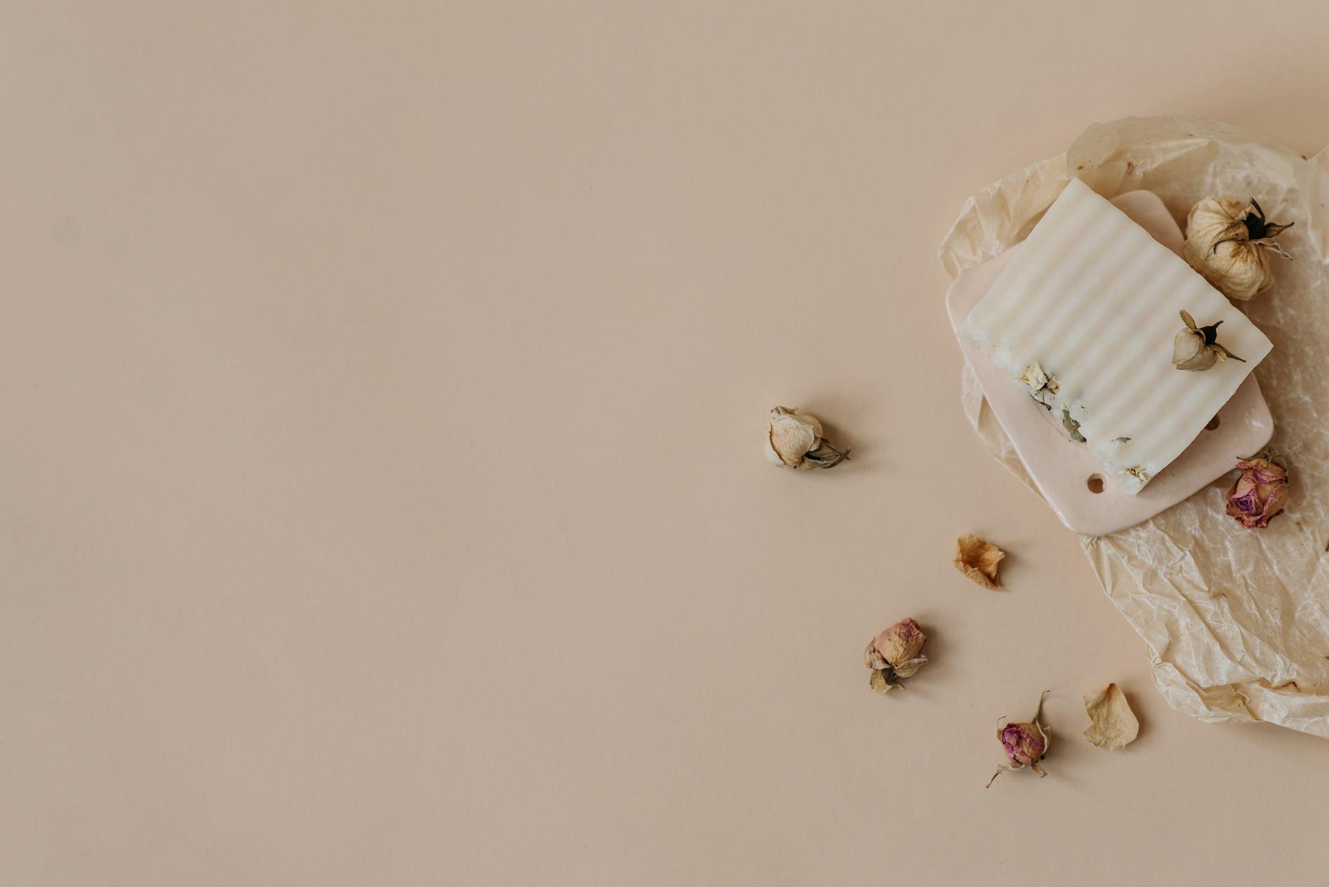 Minimalist flatlay showcasing organic handmade soap with dried flowers on beige paper.