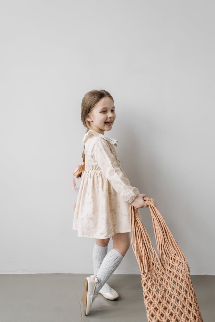 Photo Of A Kid In A Dress Holding A Bag