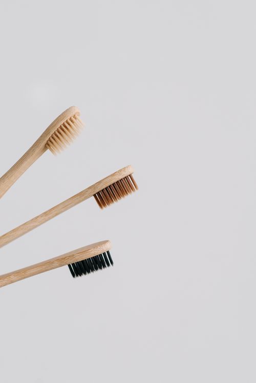 Free A close-up of three eco-friendly bamboo toothbrushes with different bristle colors on a gray background. Stock Photo