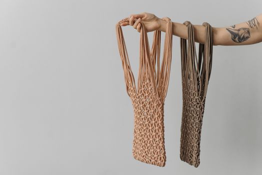 Close-up of an arm holding sustainable mesh bags showcasing tattoos.