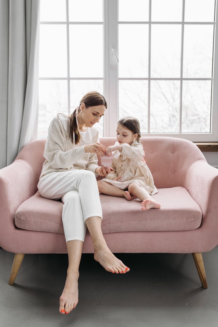 A Mother And Daughter Sitting On The Couch While Having Conversation