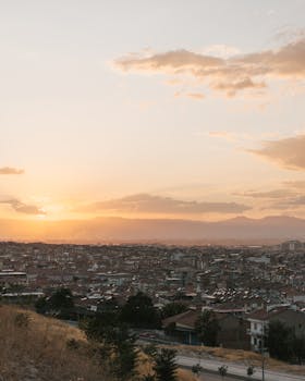 A beautiful sunrise over a sprawling urban cityscape with vibrant skies and scattered clouds.