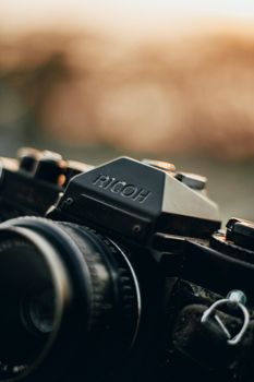 A vintage Ricoh camera captured in a close-up shot during sunset, evoking nostalgia.