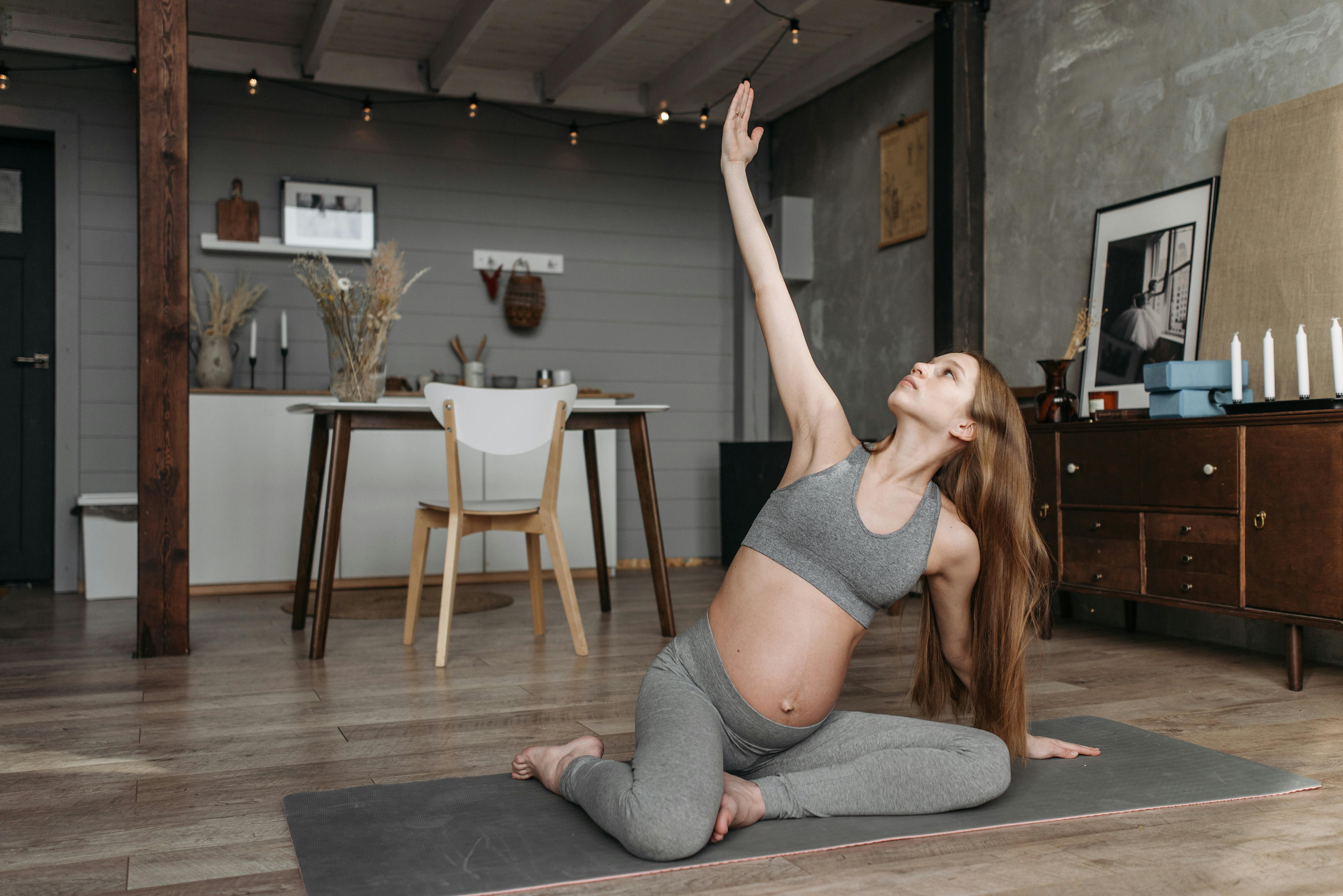 Pregnant woman practicing yoga indoors, promoting wellness and a healthy lifestyle.
