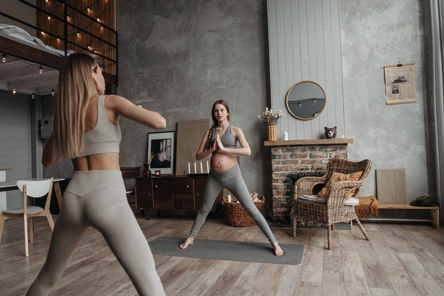 Gravid kvinne som gjør yoga sammen med en instruktør