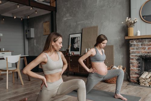 Free Two pregnant women performing yoga indoors, promoting a healthy lifestyle through exercise. Stock Photo