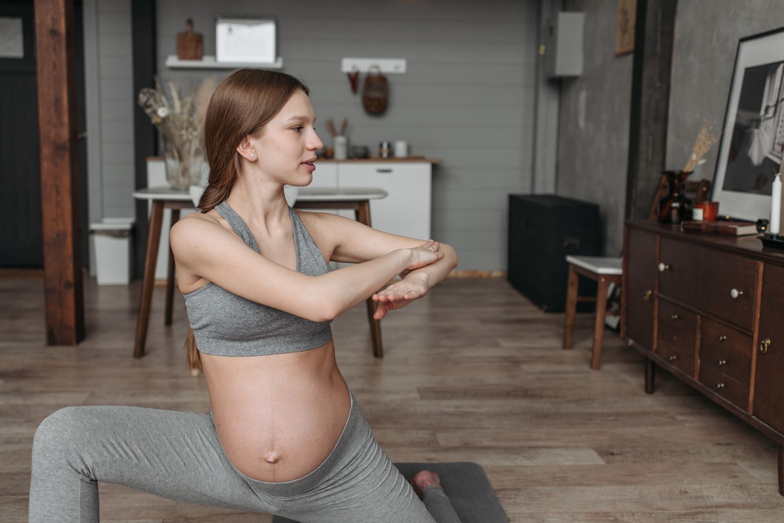 Pregnant woman in a supported seated yoga stretch with a bolster during a prenatal yoga class