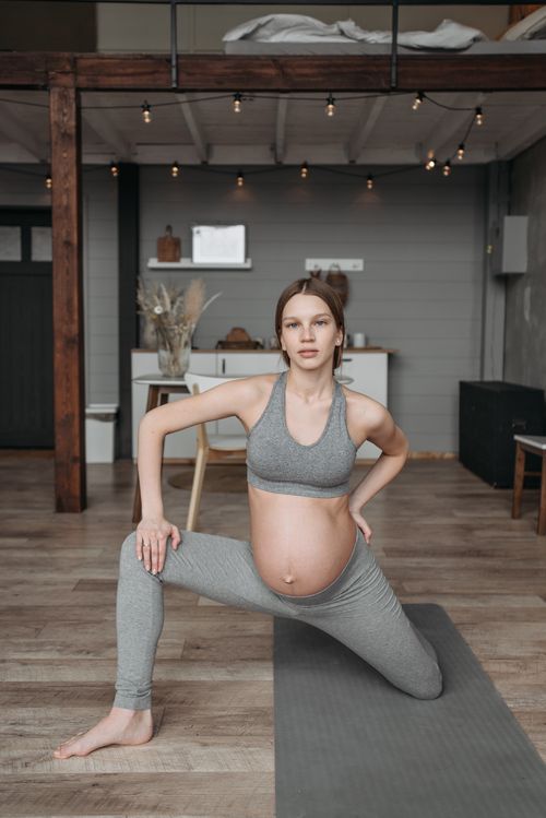 Free Pregnant woman in activewear doing yoga indoors for a healthy lifestyle. Stock Photo