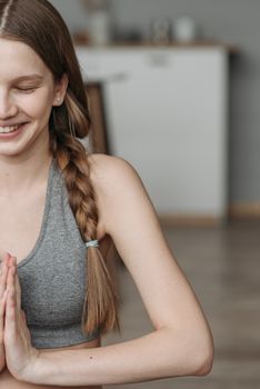 Smiling woman in activewear meditating indoors for a healthy lifestyle.