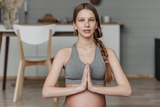 A pregnant woman in activewear practicing yoga indoors, promoting fitness and wellness.