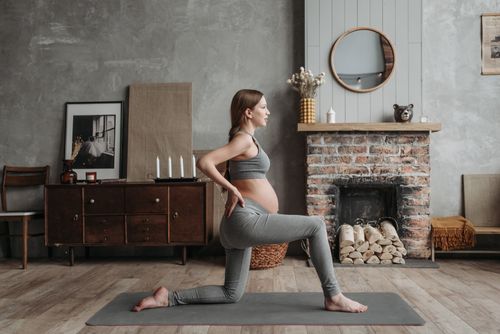 Free A pregnant woman doing yoga on a mat in a cozy living room setting. Stock Photo