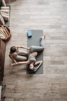 A pregnant woman stretches with a trainer on a yoga mat indoors, promoting prenatal fitness.