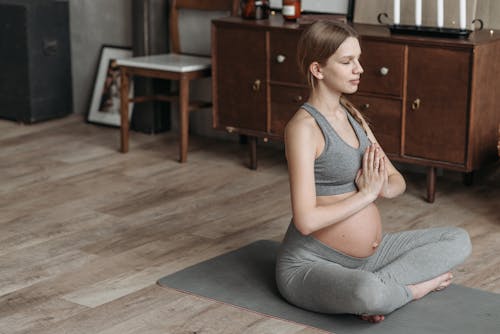 A Pregnant Woman Meditating while Sitting on Yoga Mat