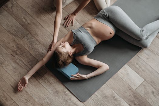 Pregnant woman doing yoga at home with guidance, emphasizing fitness and relaxation.