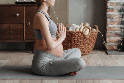 Free A Pregnant Woman Wearing Gray Tank Top Meditating  Stock Photo