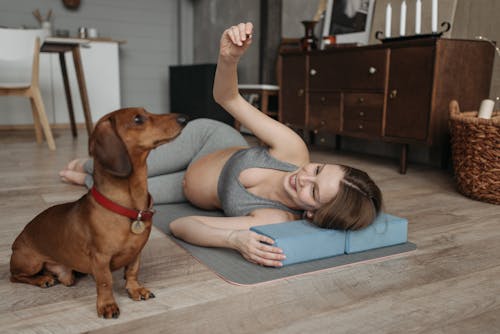 Free A Pregnant Woman Lying Over a Yoga Mat Besides Her Dog Stock Photo