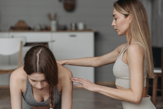 Two women engaged in a yoga session indoors, focusing on healthy lifestyle and fitness.