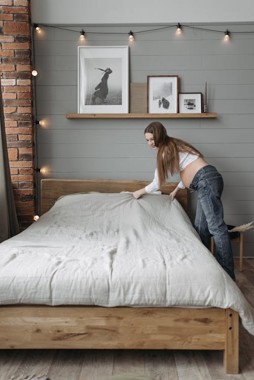 Photo of a Pregnant Woman Fixing a Bed