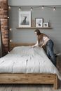 Woman in White Tank Top and Blue Denim Jeans Sitting on Bed