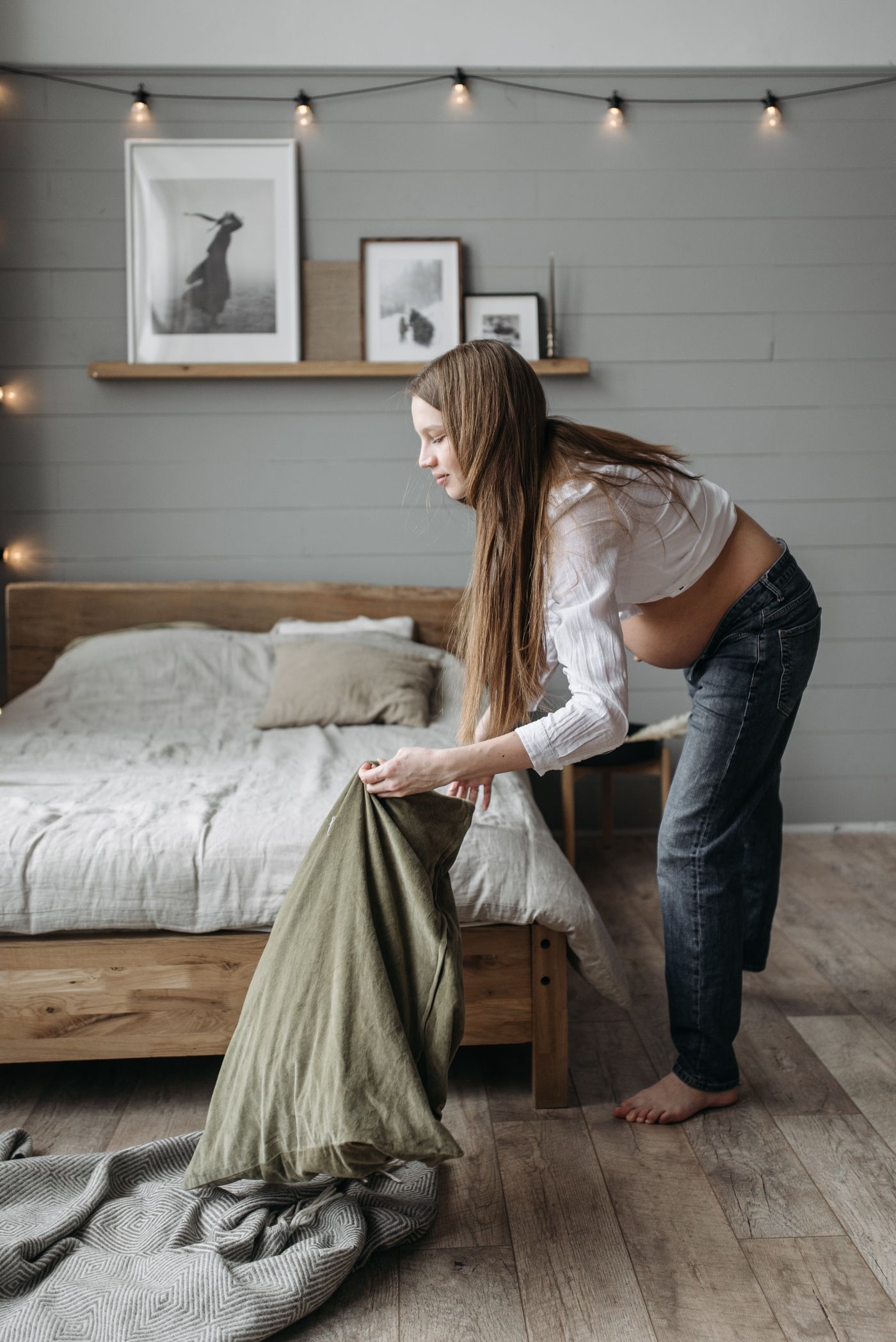 Future maman installant un oreiller dans une chambre lumineuse et accueillante