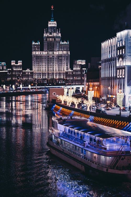 Illuminated Ferry Boat Near City Buildings at Night