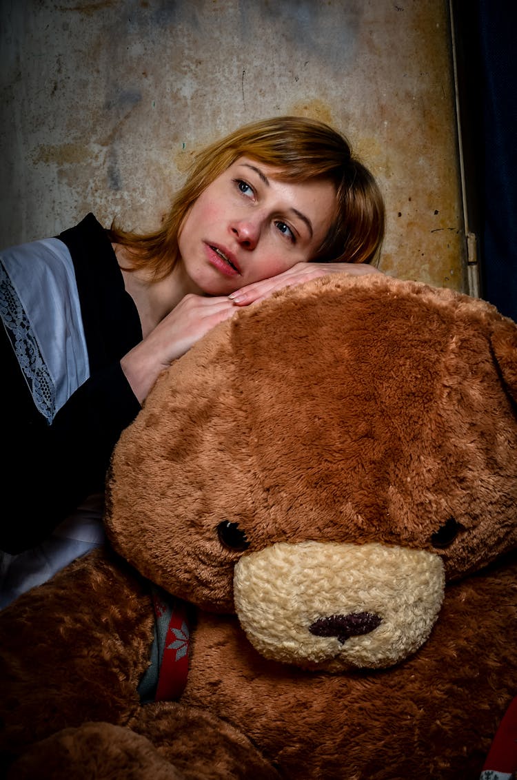 Dreamy Woman In School Wear Leaning On Plush Bear