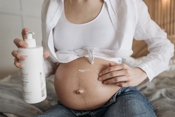 孕婦在腹部塗抹妊娠紋護理乳霜的特寫