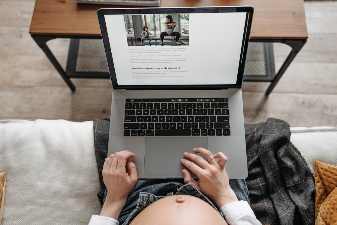 Free A Pregnant Woman Watching Exercises on a Laptop Screen Stock Photo