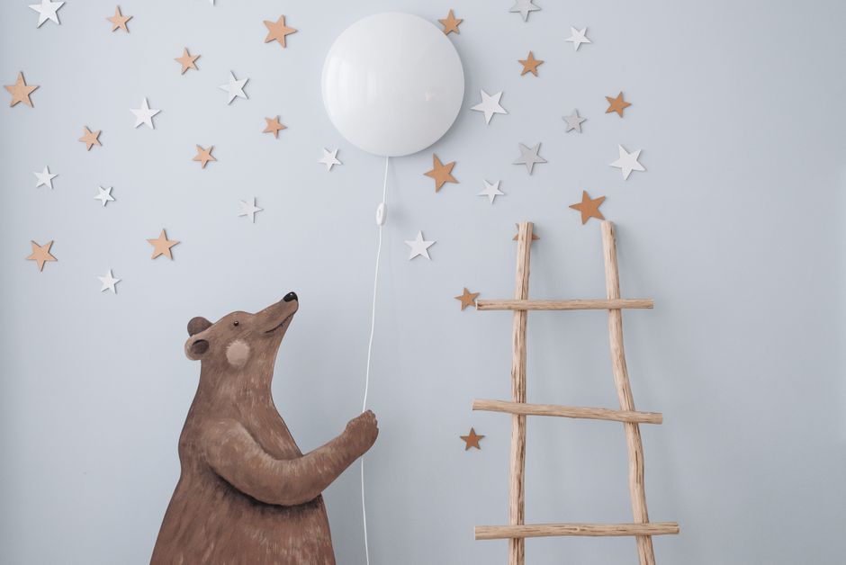 Charming nursery decor featuring a bear with a balloon, stars, and a wooden ladder for playful ambiance.