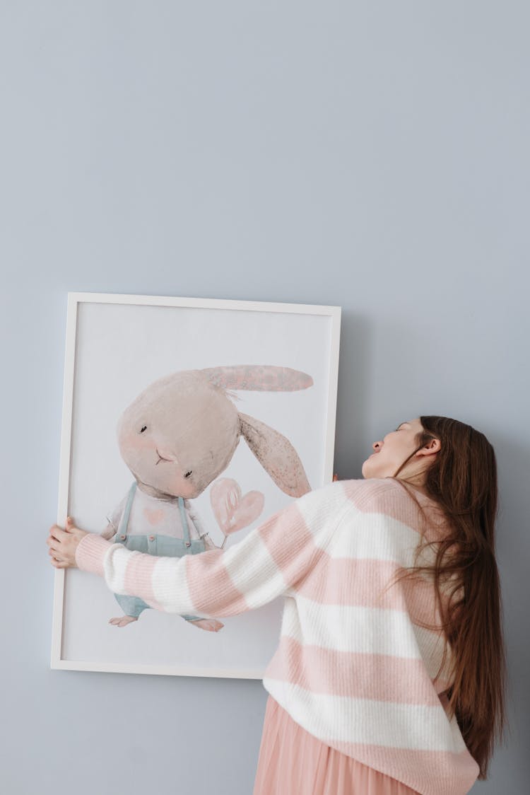 Photo Of A Woman Hanging A Picture Frame