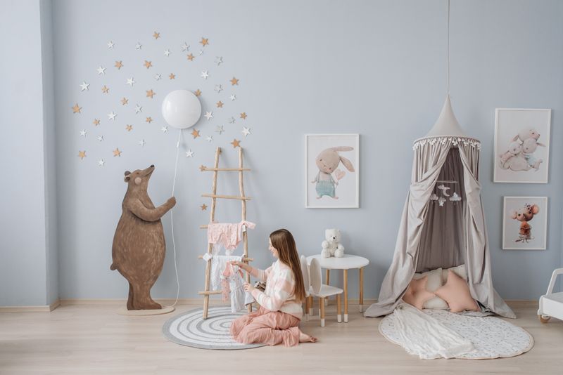 Woman arranging baby clothes in a beautifully decorated nursery with playful decor.