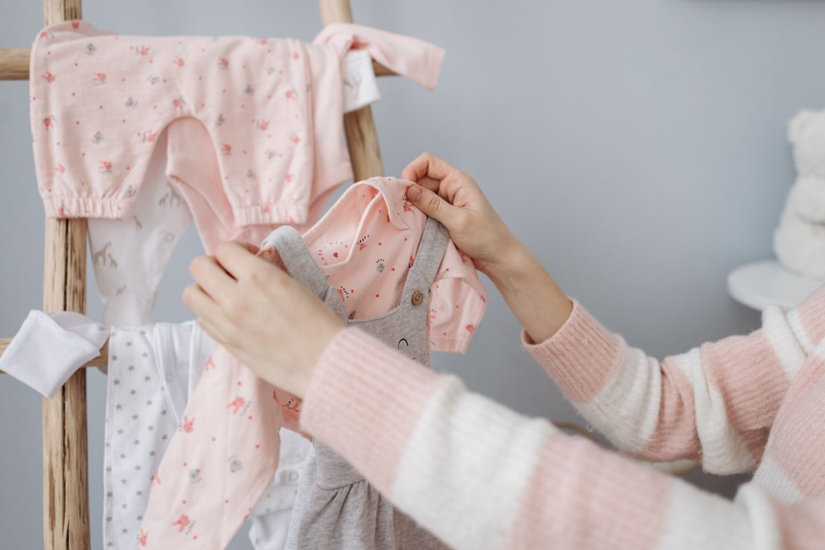 A mother organising baby clothes on a wooden rack indoors