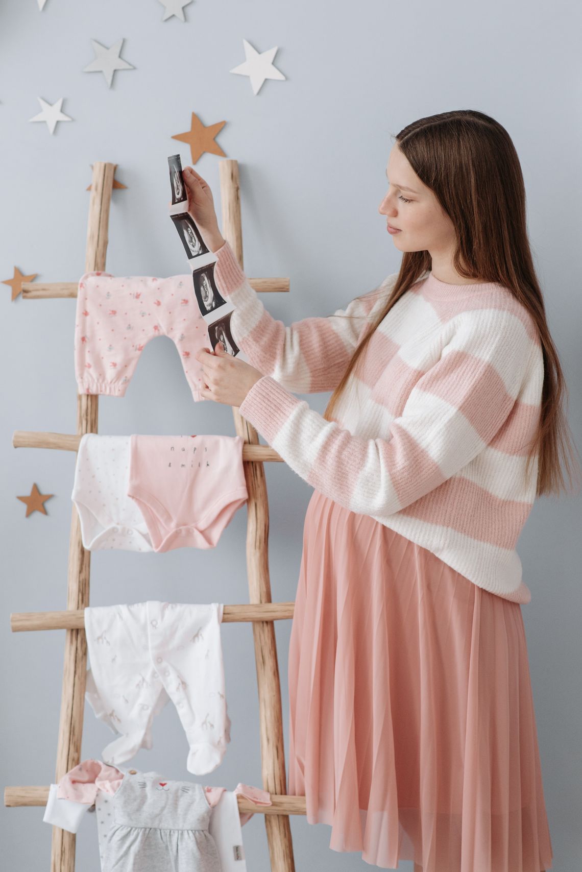 Pregnant mother looking at an ultrasound while preparing a nursery