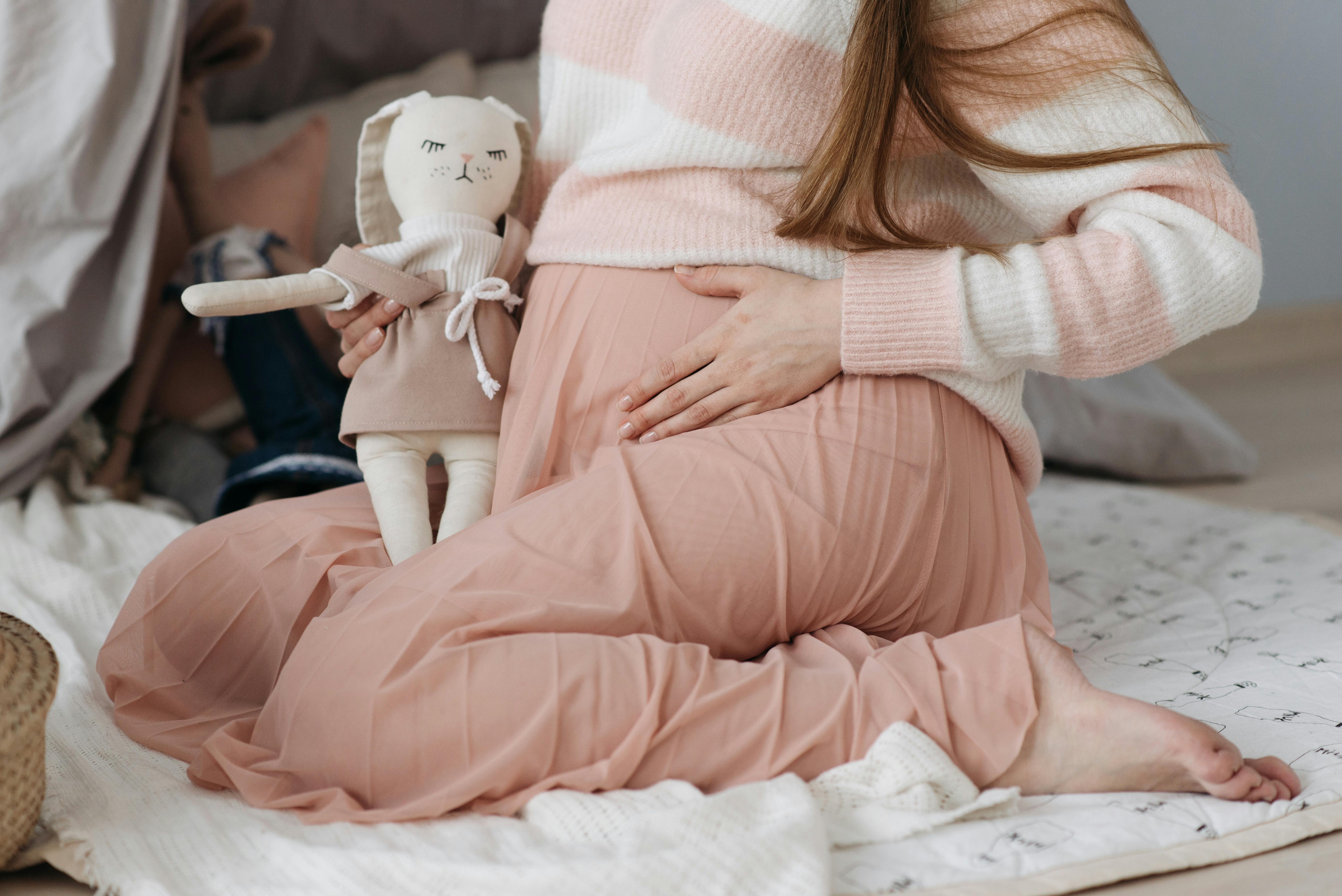 pregnant woman in pink skirt touching belly