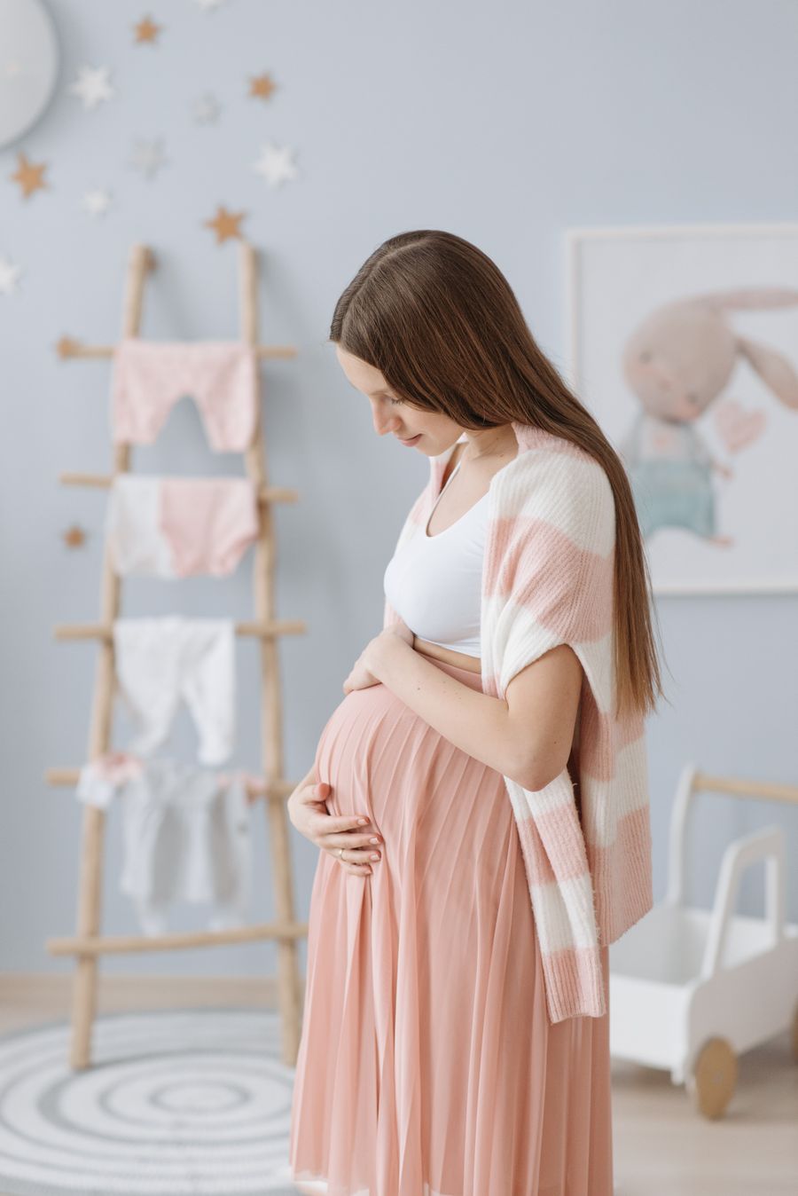 Pregnant woman caressing her baby bump in a serene nursery
