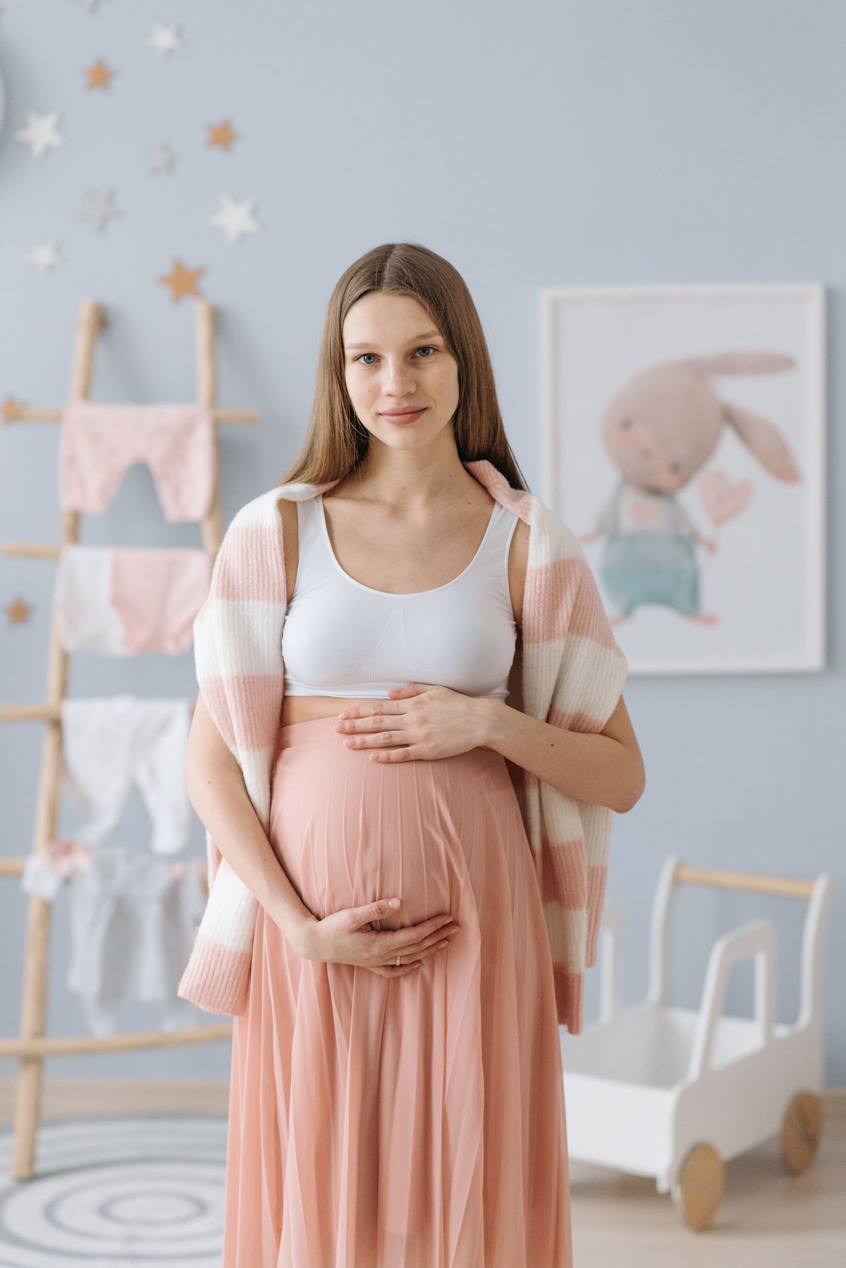 Pregnant woman holding her baby bump in a prepared nursery