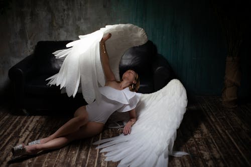Free Graceful woman wearing angel wings lying on floor Stock Photo