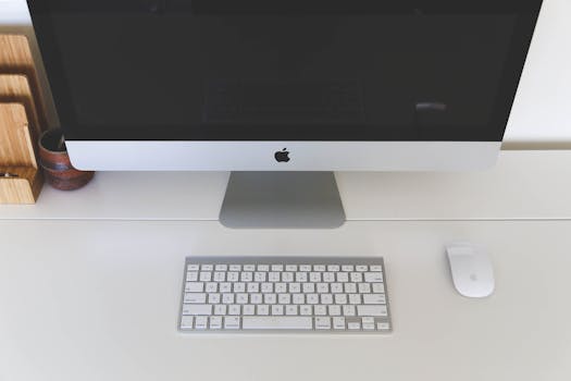 Minimalist home office workspace featuring a desktop computer, keyboard, and mouse on a white desk.