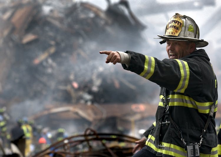 Fire Fighter Wearing Black And Yellow Uniform Pointing For Something