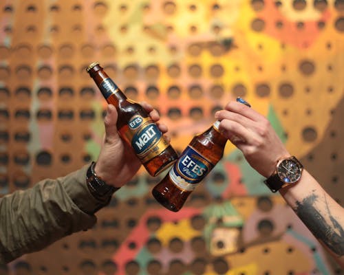 Free Close-Up Shot of Two People Holding Bottles of Beer Stock Photo