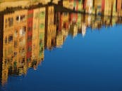 平静的水面倒映着色彩缤纷的建筑，营造出宁静、艺术的场景