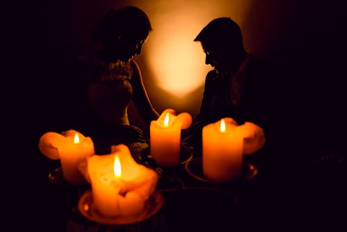 Silhouette of Man and Woman Sitting Beside Lighted Candles