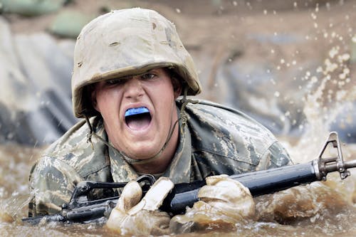 Ejército Sosteniendo Un Rifle Sobre El Agua En Fotografía De Primer Plano