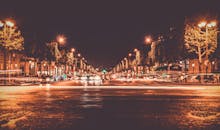 热闹的夜间城市街道上，车灯闪烁的小路与明亮的树木交织，营造出充满活力的城市氛围